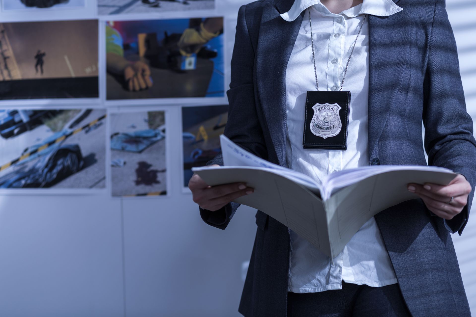 A woman in a suit and badge is holding a book.