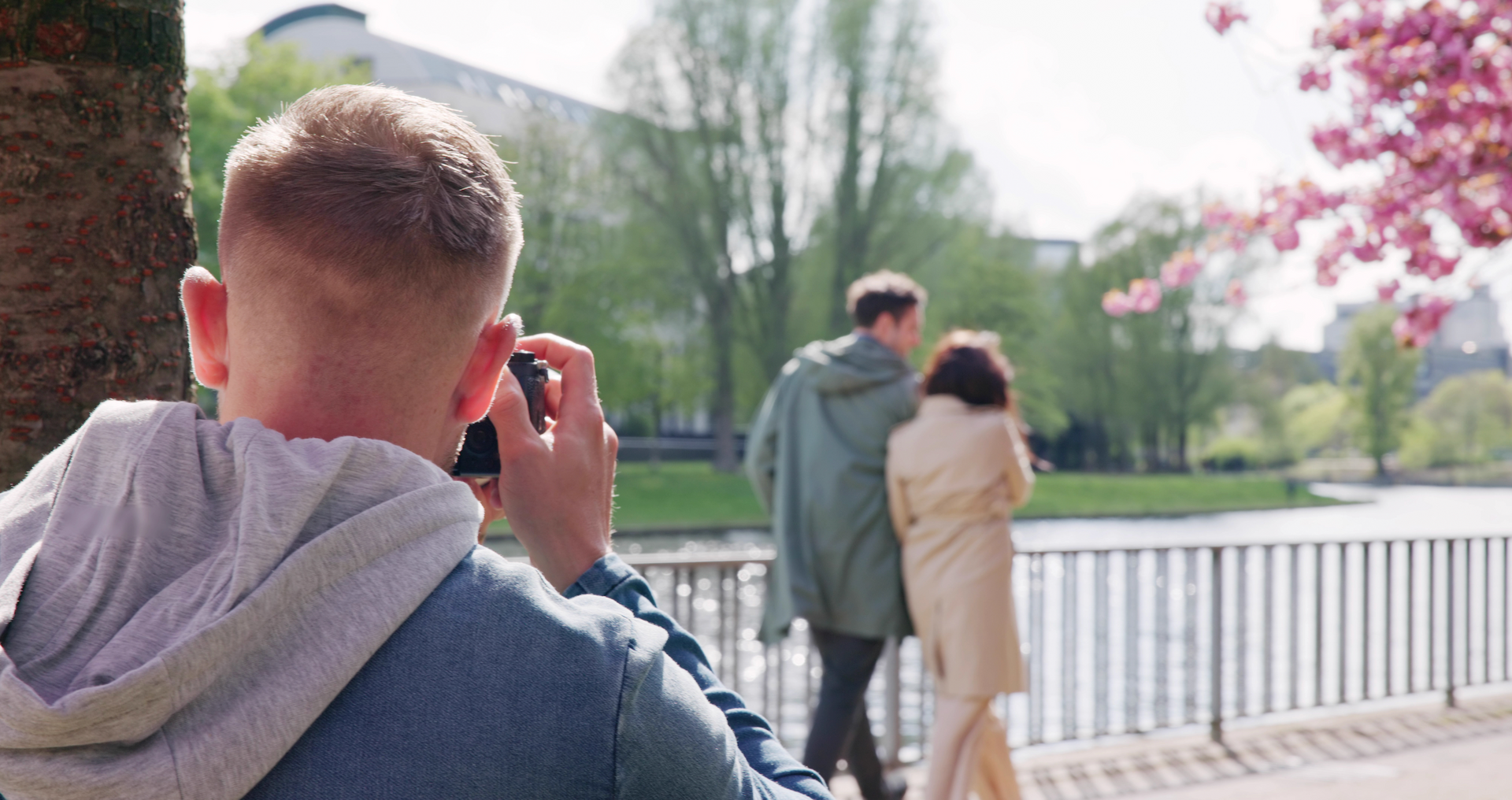 A man is taking a picture of a couple walking in a park.