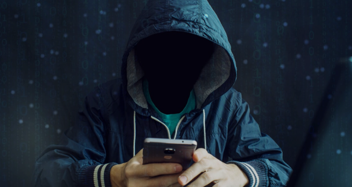 A man in a hooded jacket is using a cell phone.