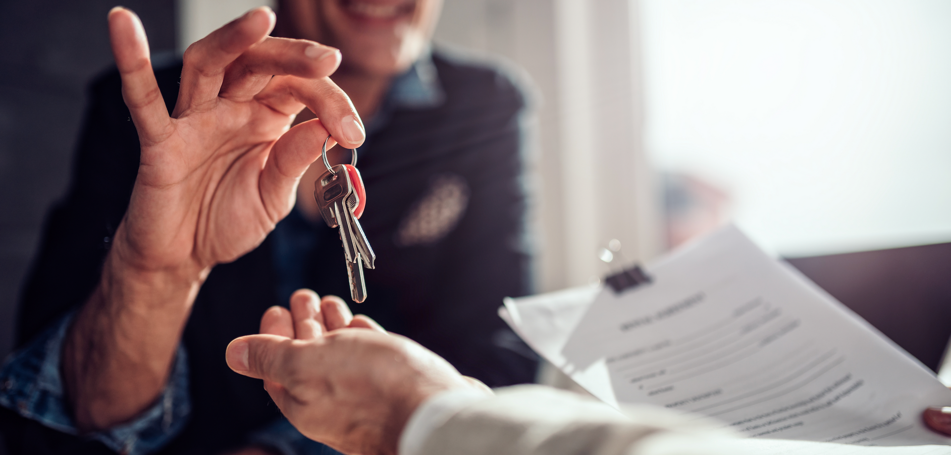 A man is giving a woman a set of keys.