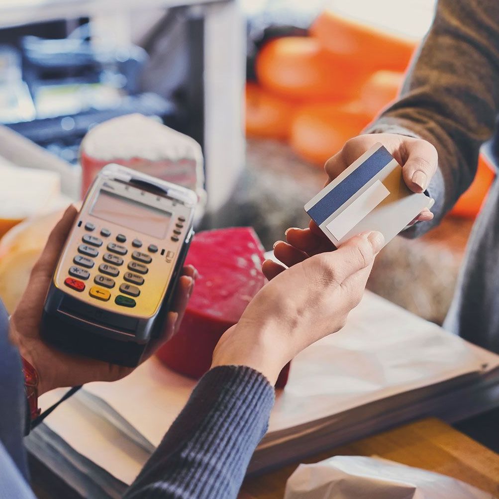 A person is holding a credit card and a credit card reader