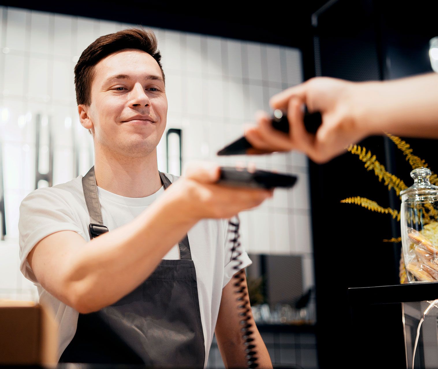 A man in an apron is giving a credit card to a customer.