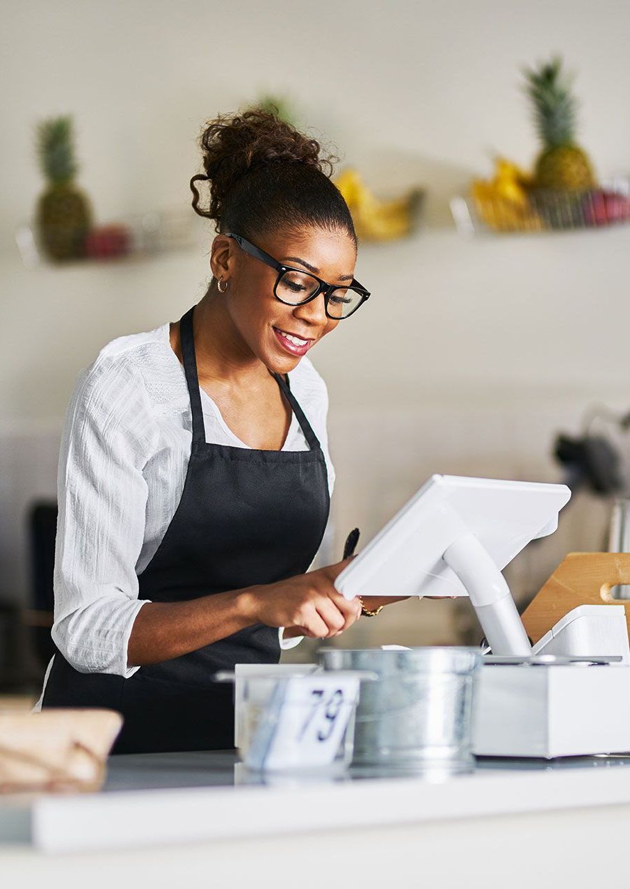 A woman in an apron is using a tablet in a restaurant.