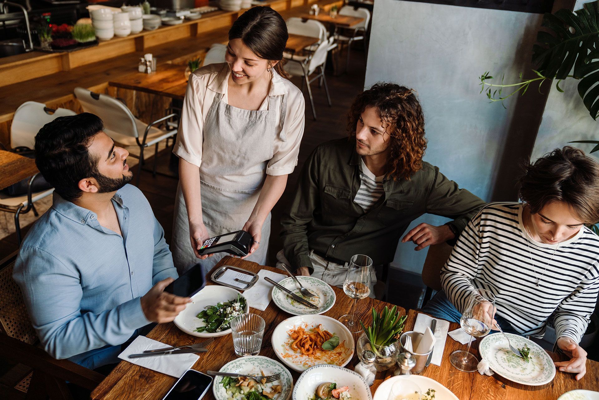 A group of people are sitting at a table in a restaurant eating food.