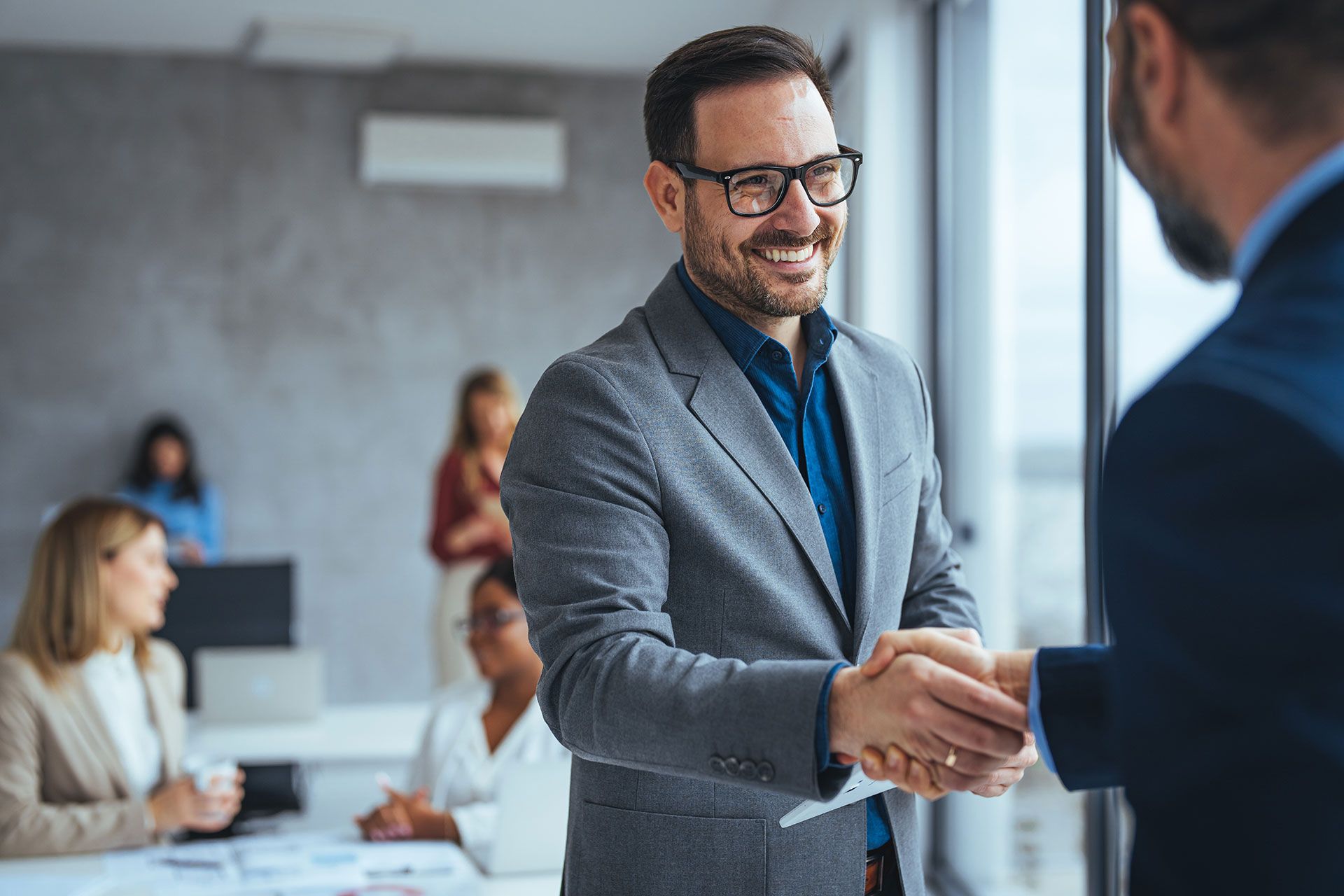 A man in a suit is shaking hands with another man in an office.