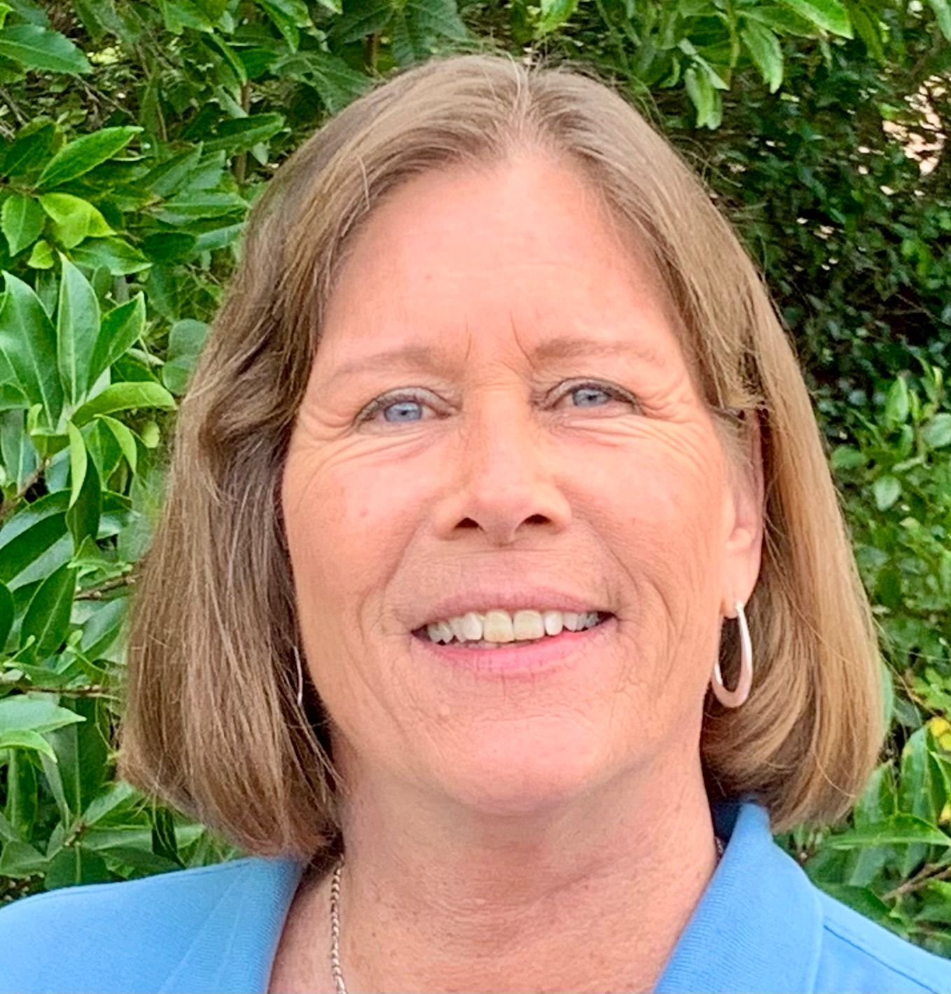 A woman in a blue shirt is smiling for the camera.