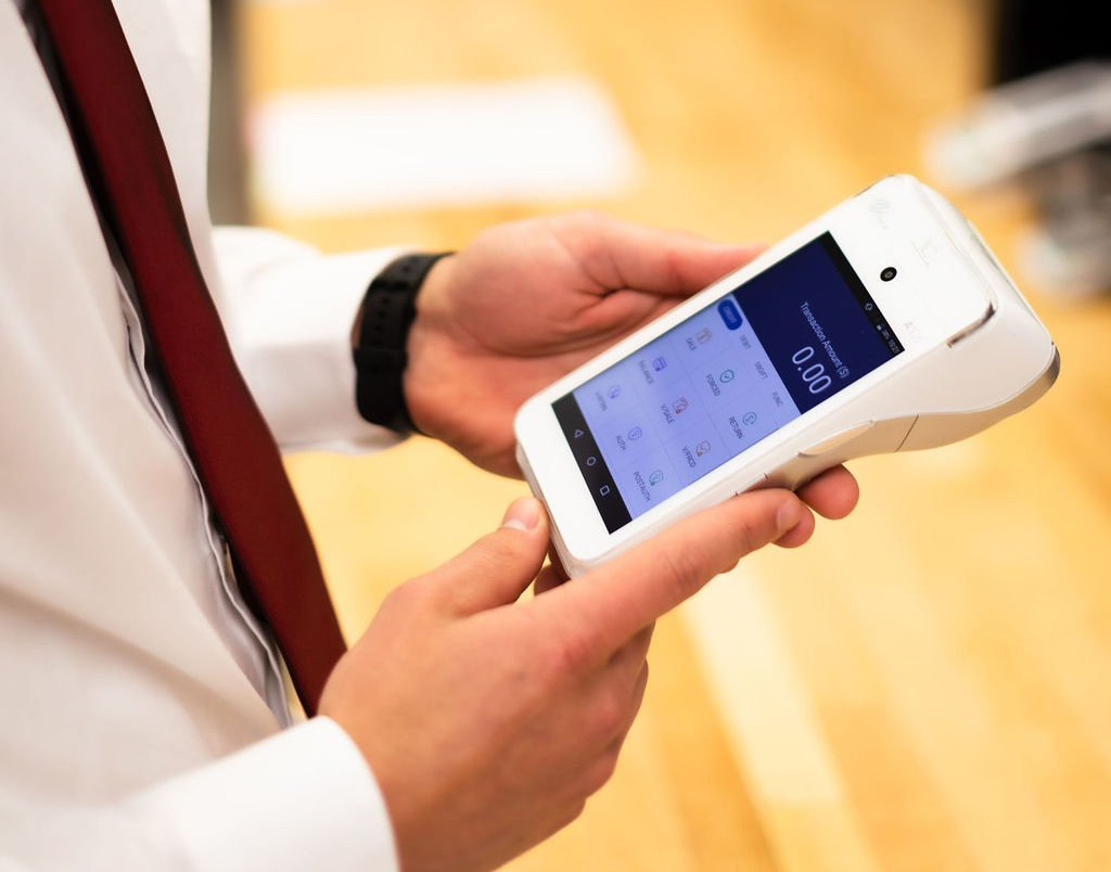 A man in a white shirt and red tie is holding a cell phone in his hands.