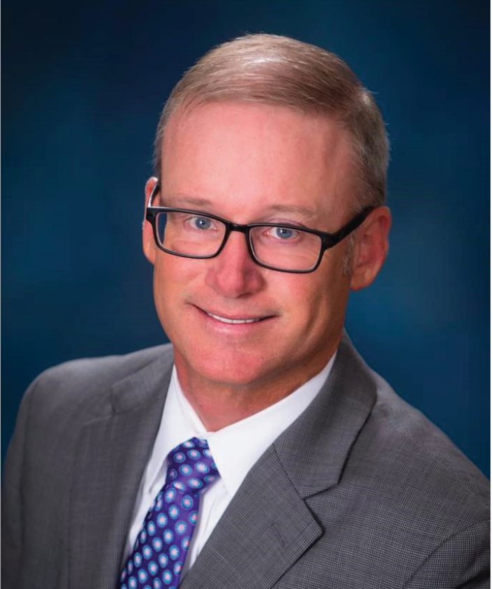 A man in a suit and tie is smiling for the camera