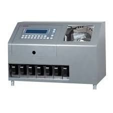 Máquina contadora de monedas de color gris, con teclado, pantalla y múltiples ranuras de salida.