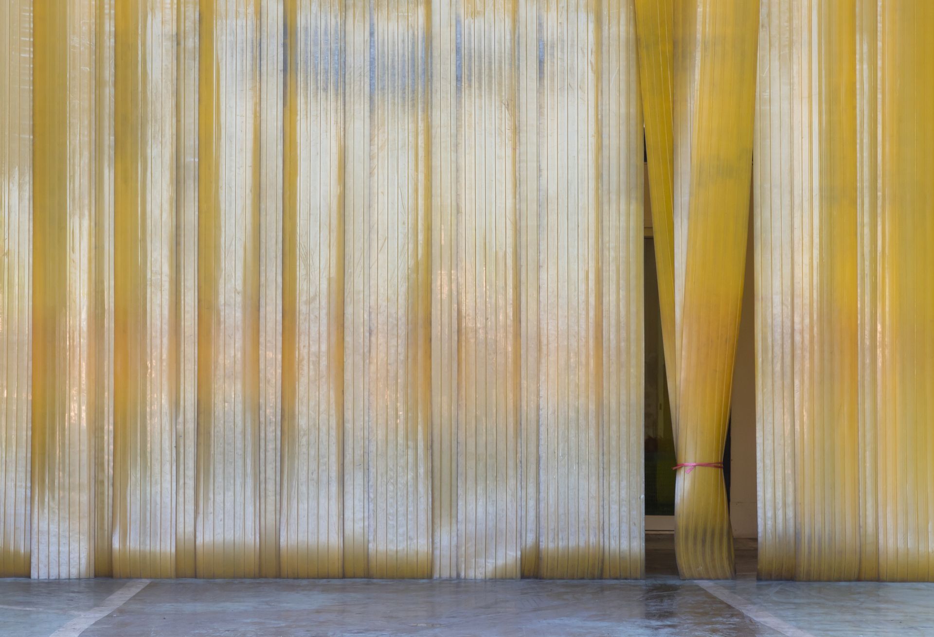 A yellow curtain is hanging on a wall in a room.