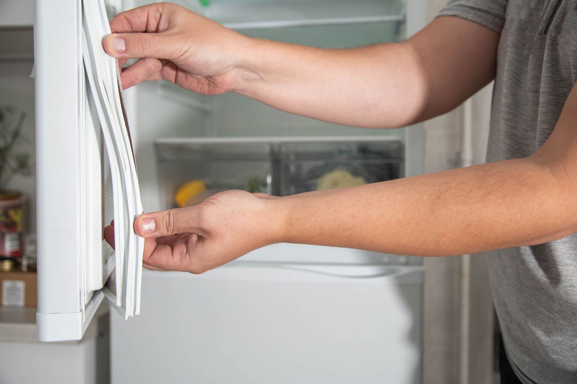 A man is opening the door of a refrigerator.