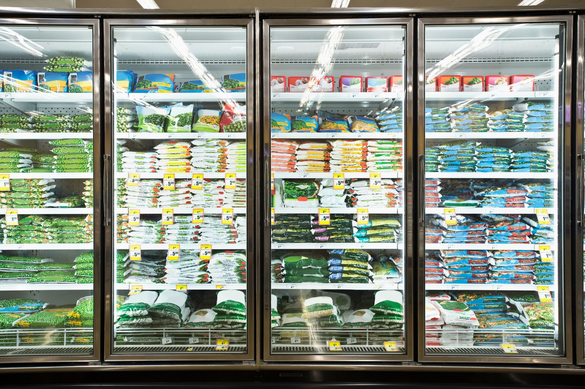 A grocery store refrigerator filled with lots of frozen foods.