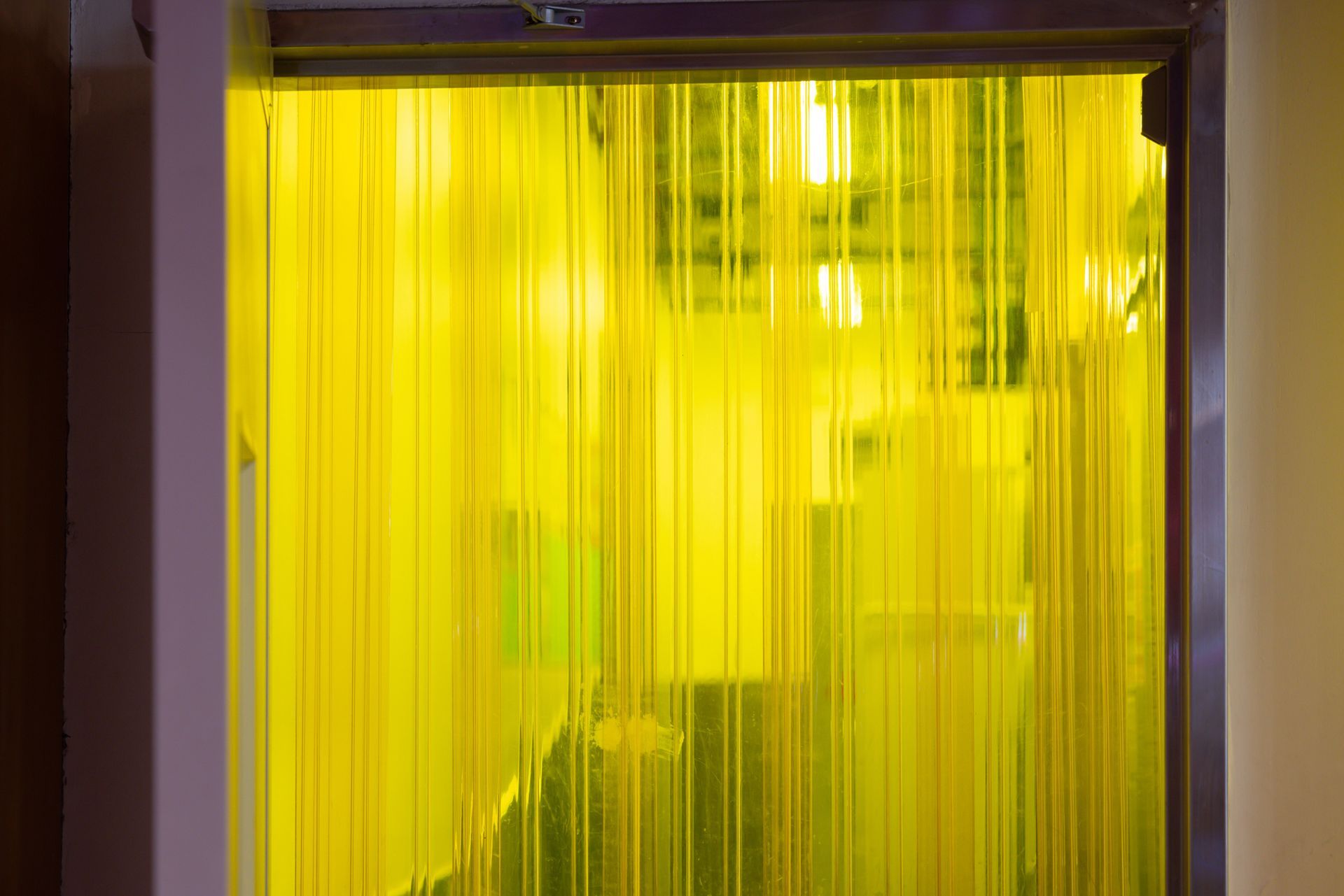 A yellow curtain is hanging on a window in a room.