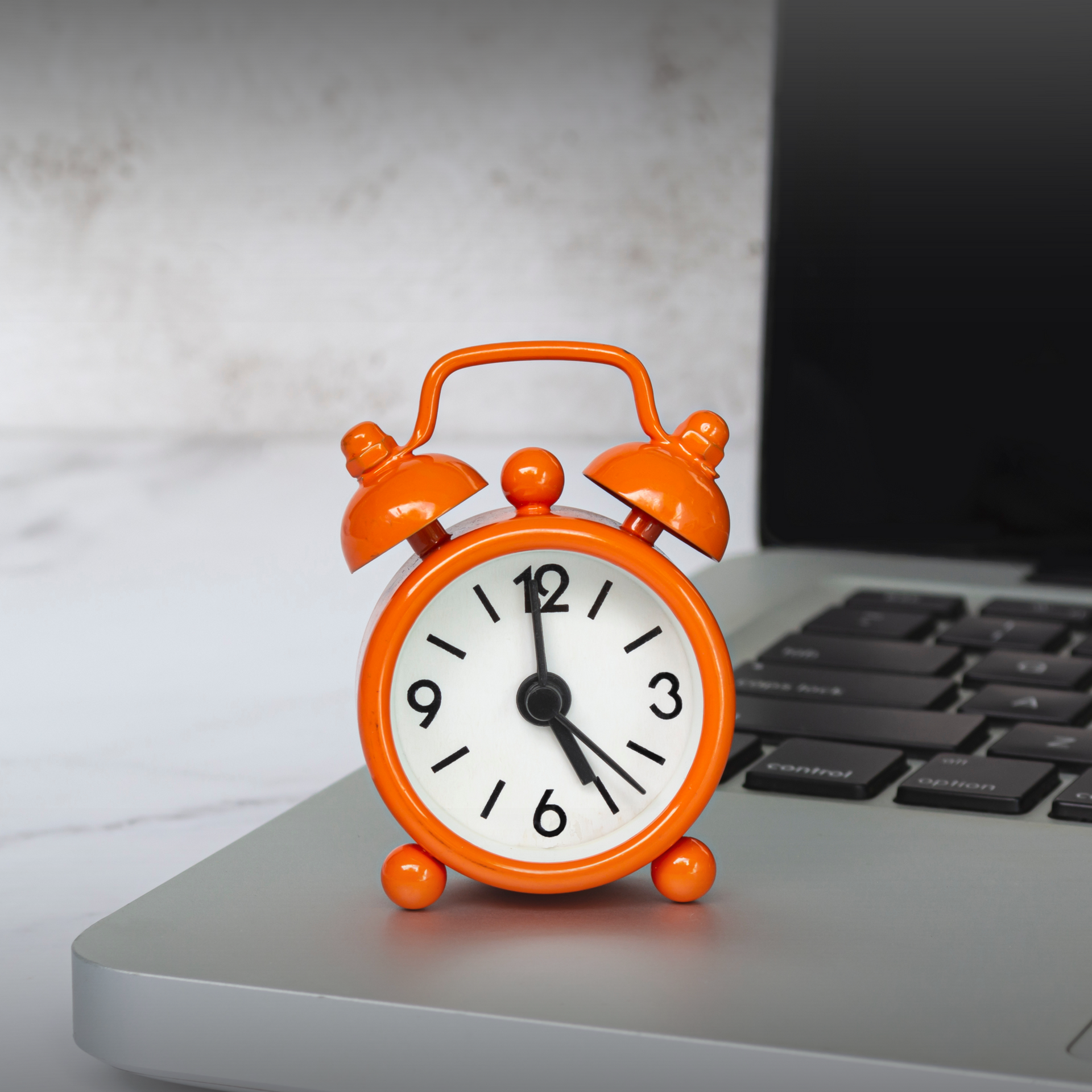 An orange clock on a laptop symbolizing daylight savings and claim timing risks of Sunset clauses.