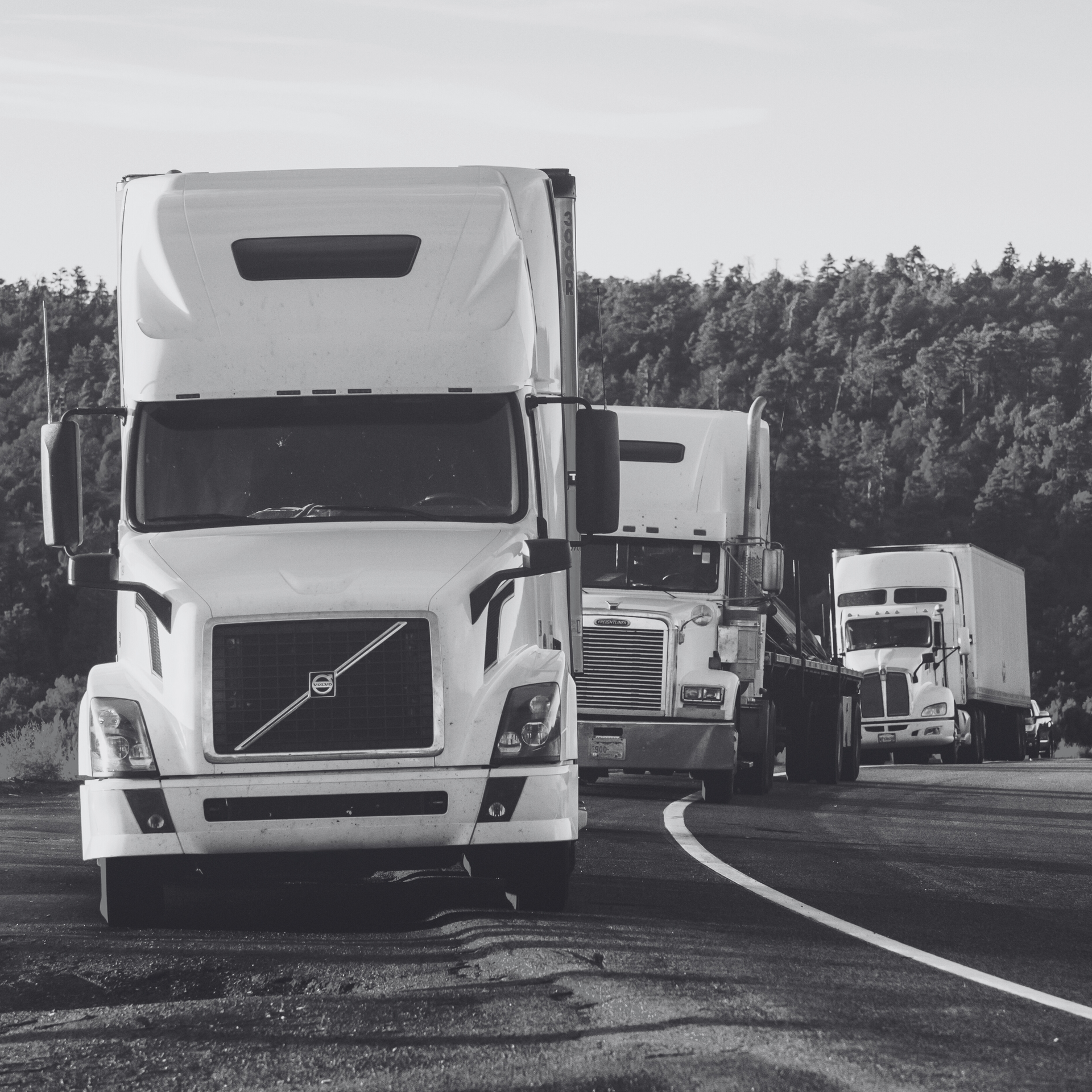 Small fleet of trucks on highway representing Small Fleet Truckers Occupational Accident Insurance.