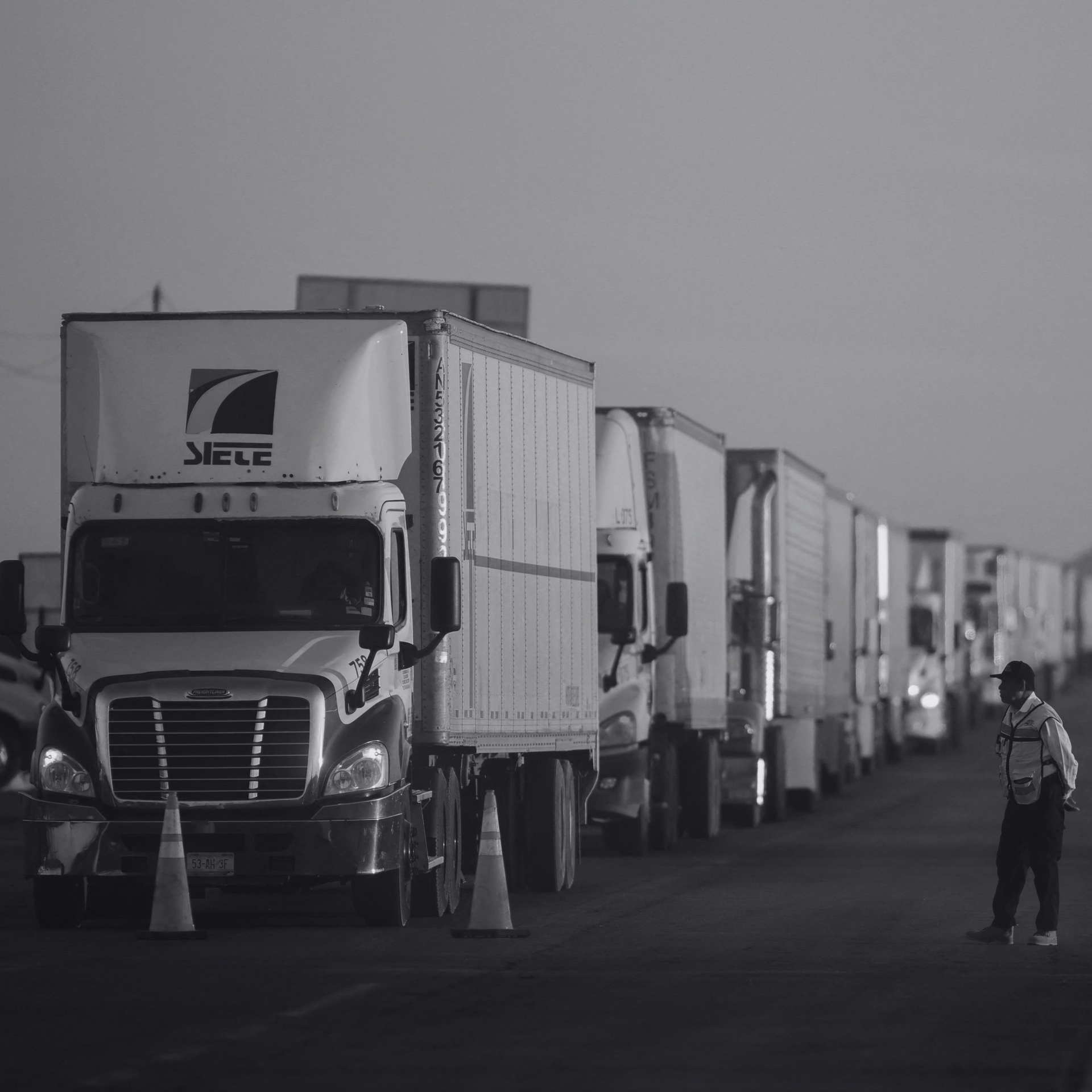 Trucks queued at the U.S.-Mexico border amid $415B trade, highlighting demand for B-1 Visa Truckers.