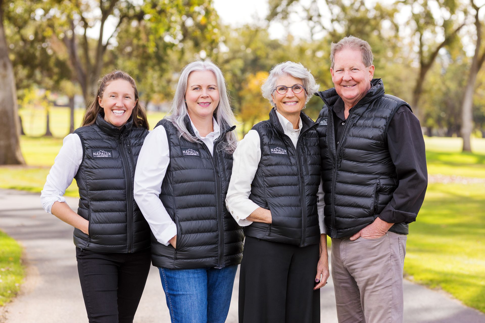 A group of people wearing black vests are posing for a picture.