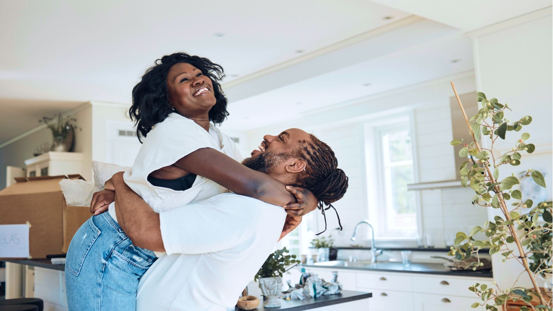 A man is carrying a woman on his shoulders in a kitchen.