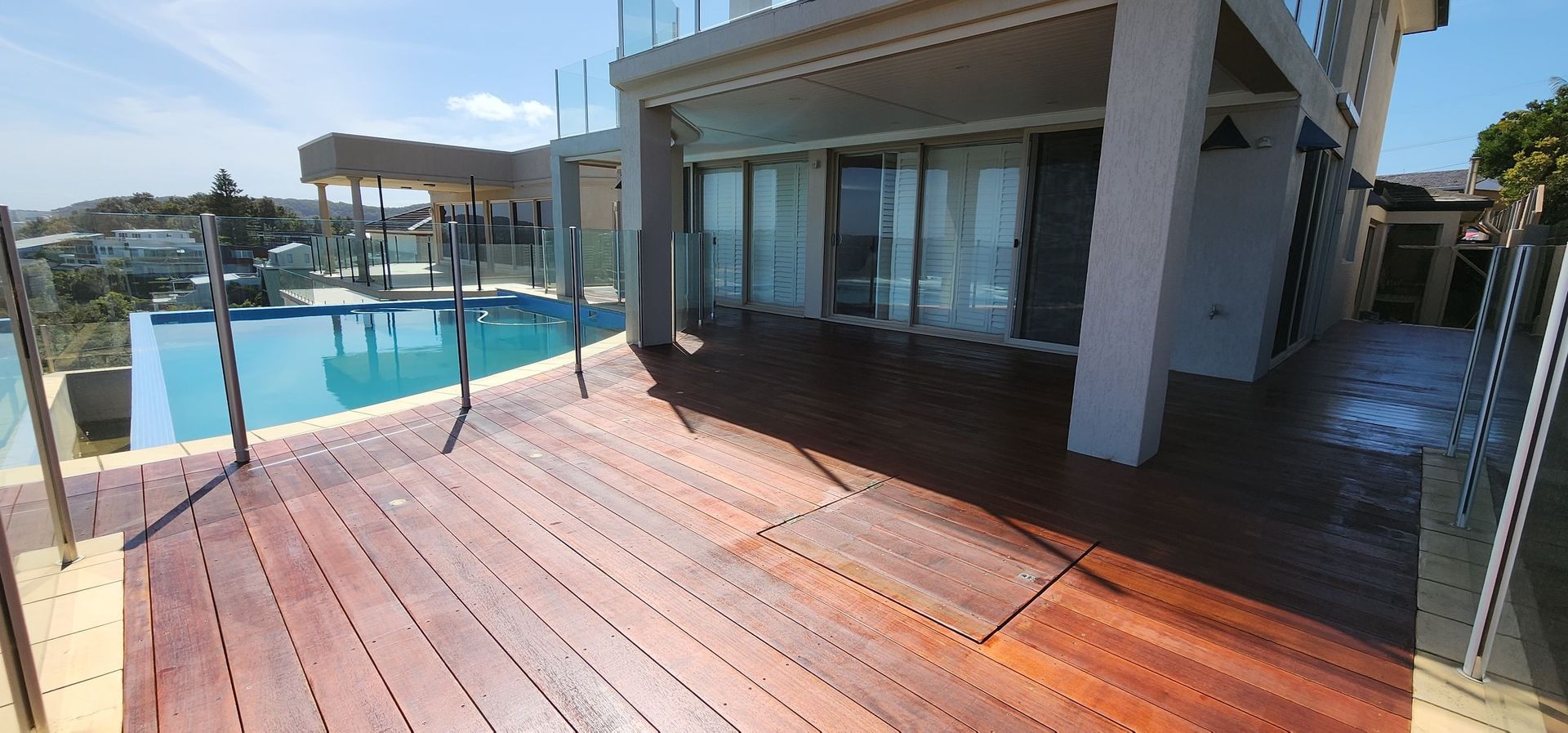 A Large Wooden Deck With a Swimming Pool in the Background — JAX Painting Services in Central Coast, NSW