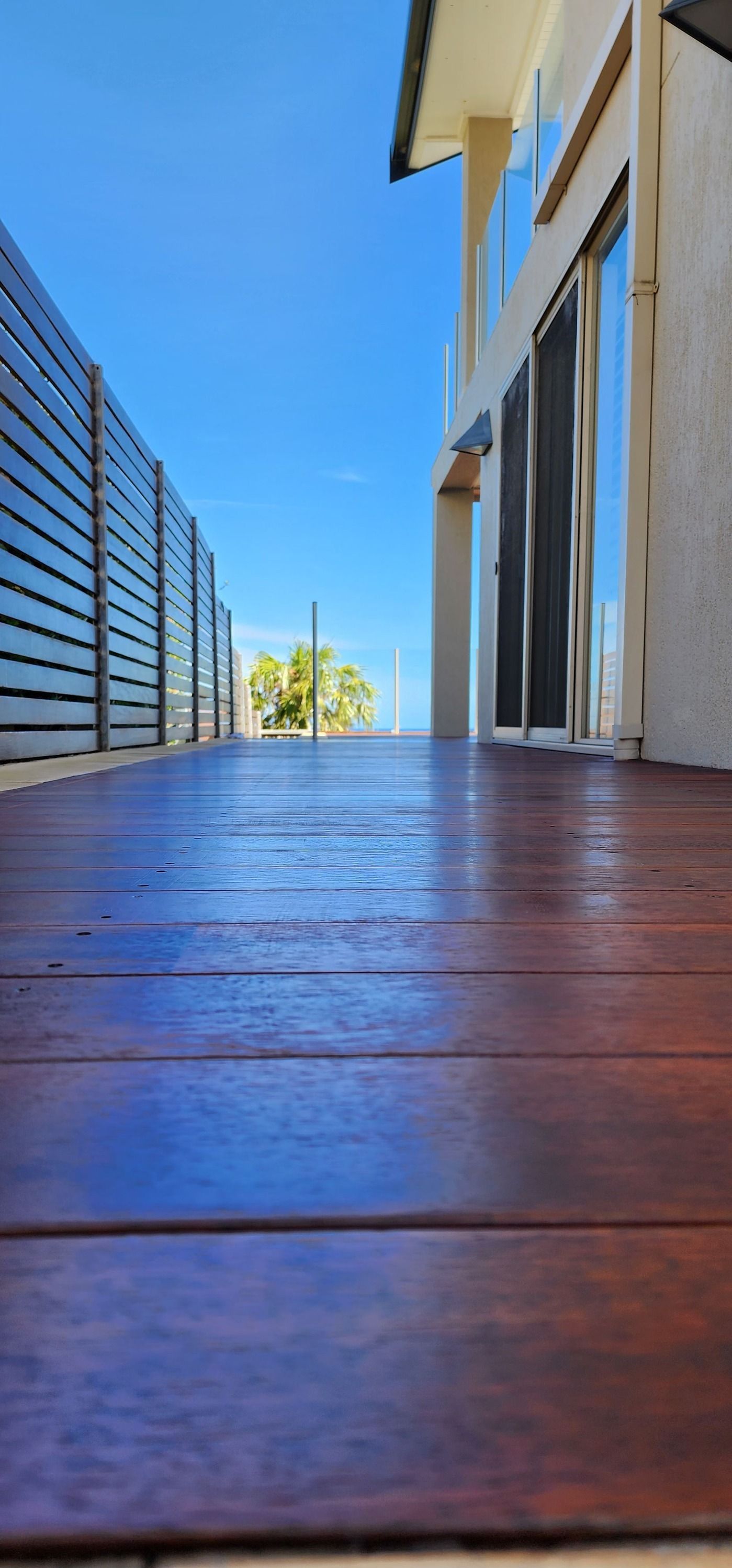 A Wooden Deck Leading to a House With a Blue Sky in the Background — JAX Painting Services in Central Coast, NSW