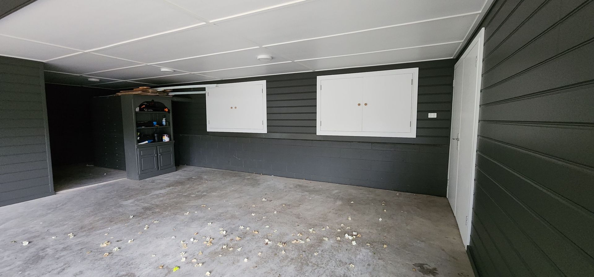 An Empty Garage With Black Walls and White Doors — JAX Painting Services in Central Coast, NSW