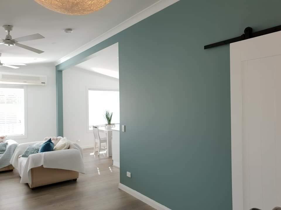 A Living Room With a Couch, Chair, Ceiling Fan and Sliding Barn Door — JAX Painting Services in Central Coast, NSW