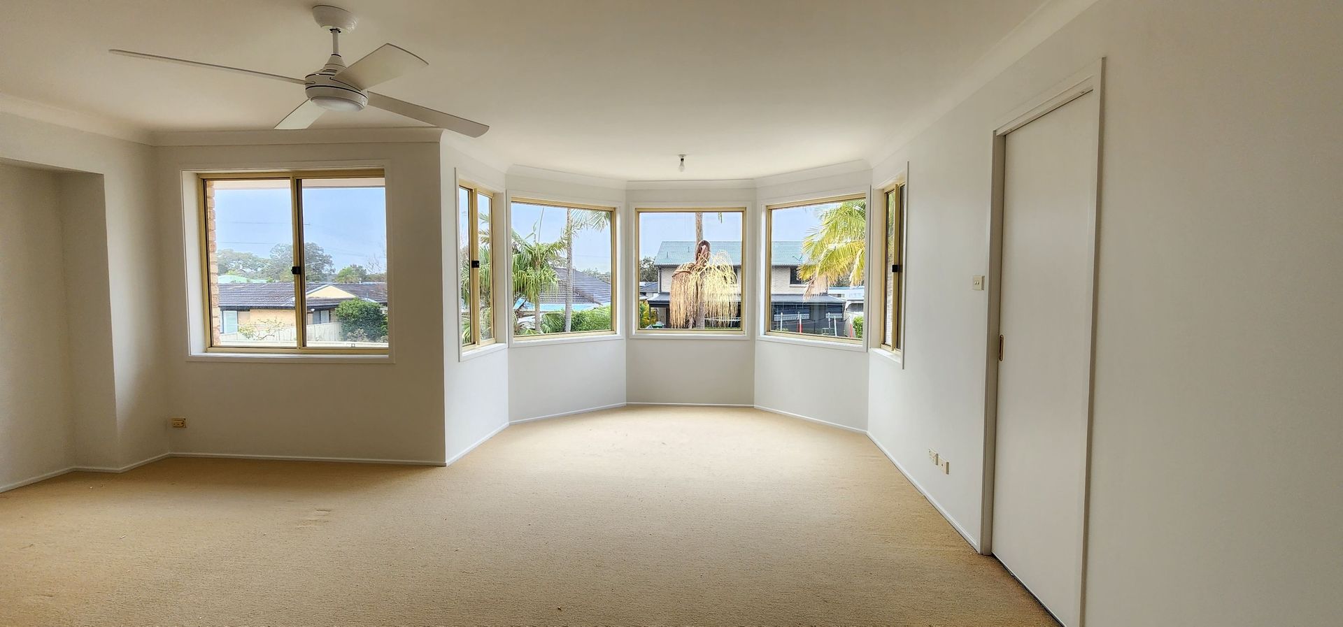 An Empty Living Room With a Lot of Windows and a Ceiling Fan — JAX Painting Services in Central Coast, NSW