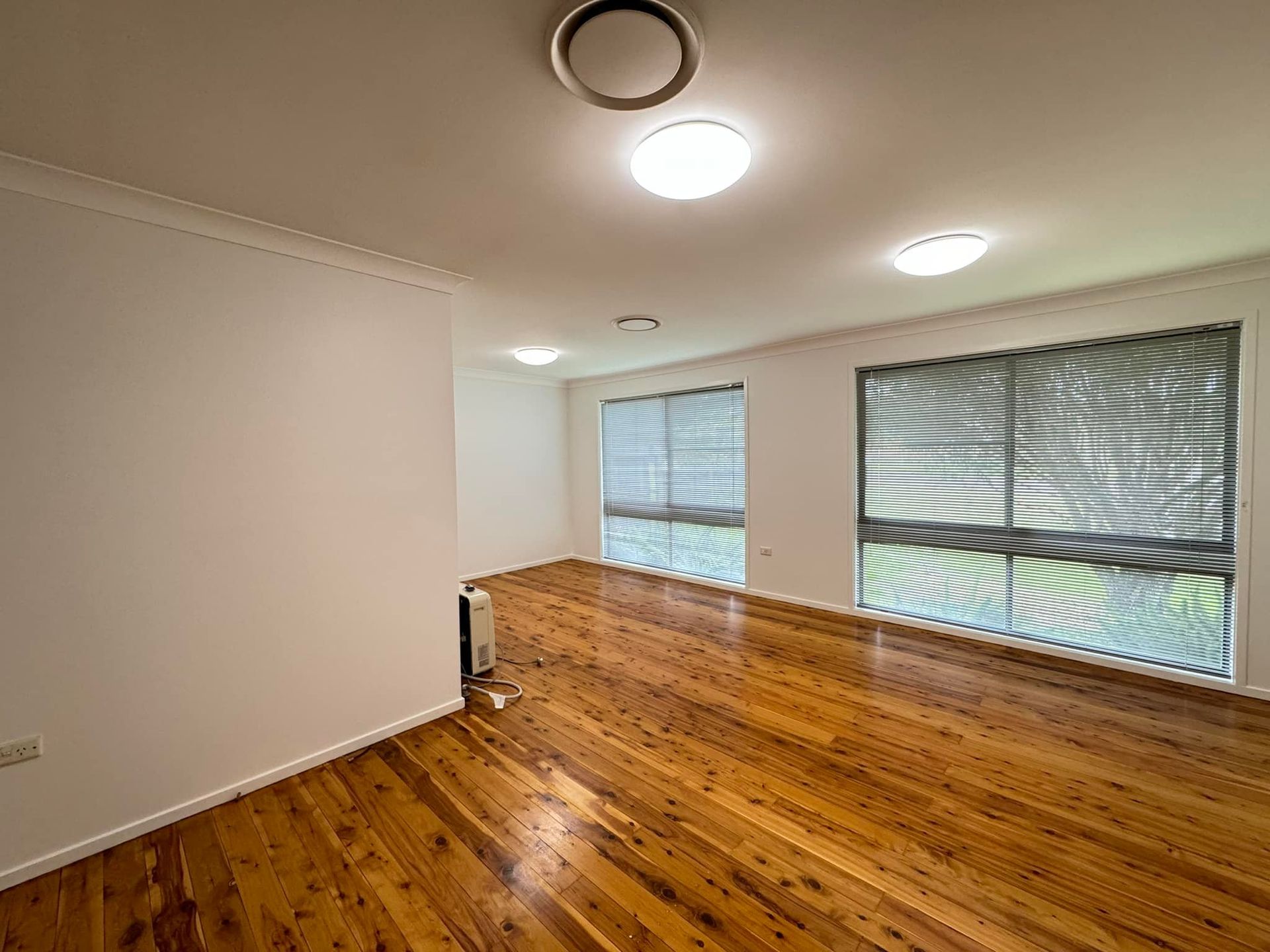 An Empty Room With Wooden Floors and White Walls — JAX Painting Services in Central Coast, NSW
