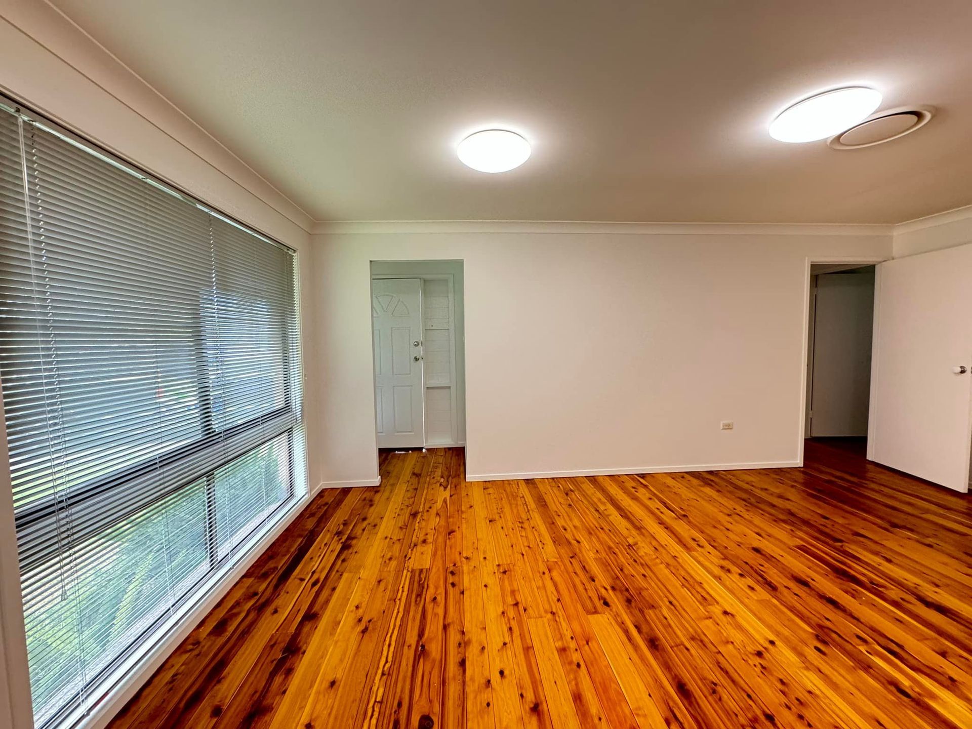 An Empty Room With Wooden Floors and Blinds on the Windows — JAX Painting Services in Central Coast, NSW
