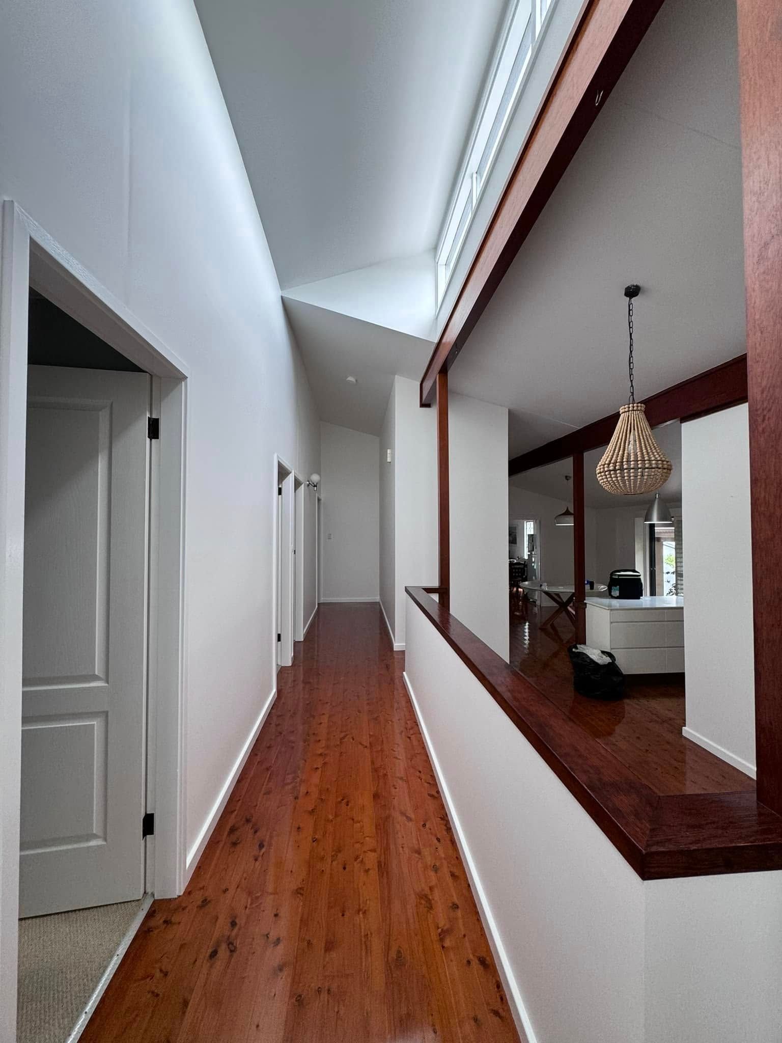 A Long Hallway With Hardwood Floors and White Walls — JAX Painting Services in Central Coast, NSW