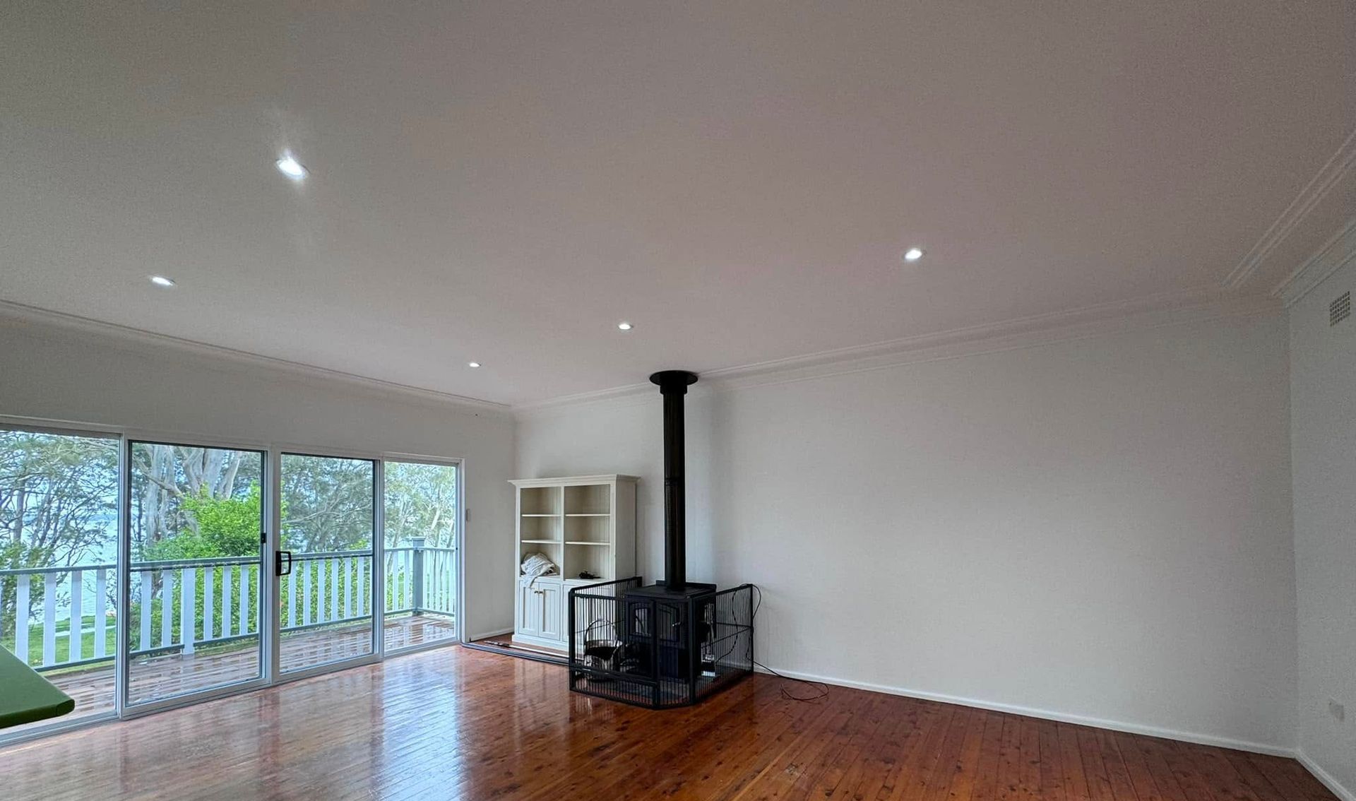An Empty Living Room With Hardwood Floors and a Fireplace — JAX Painting Services in Central Coast, NSW