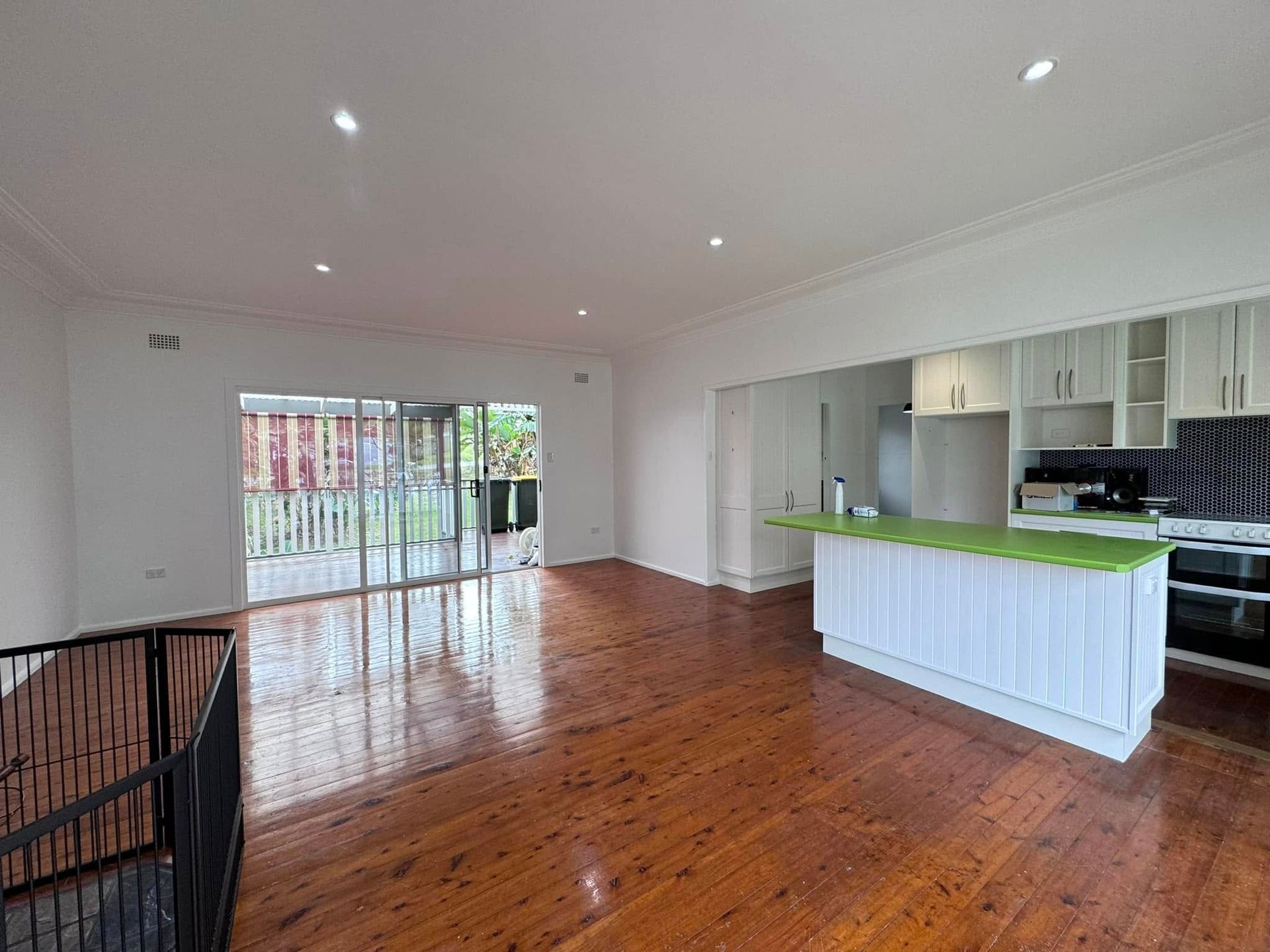 An Empty Living Room With Hardwood Floors and a Kitchen — JAX Painting Services in Central Coast, NSW