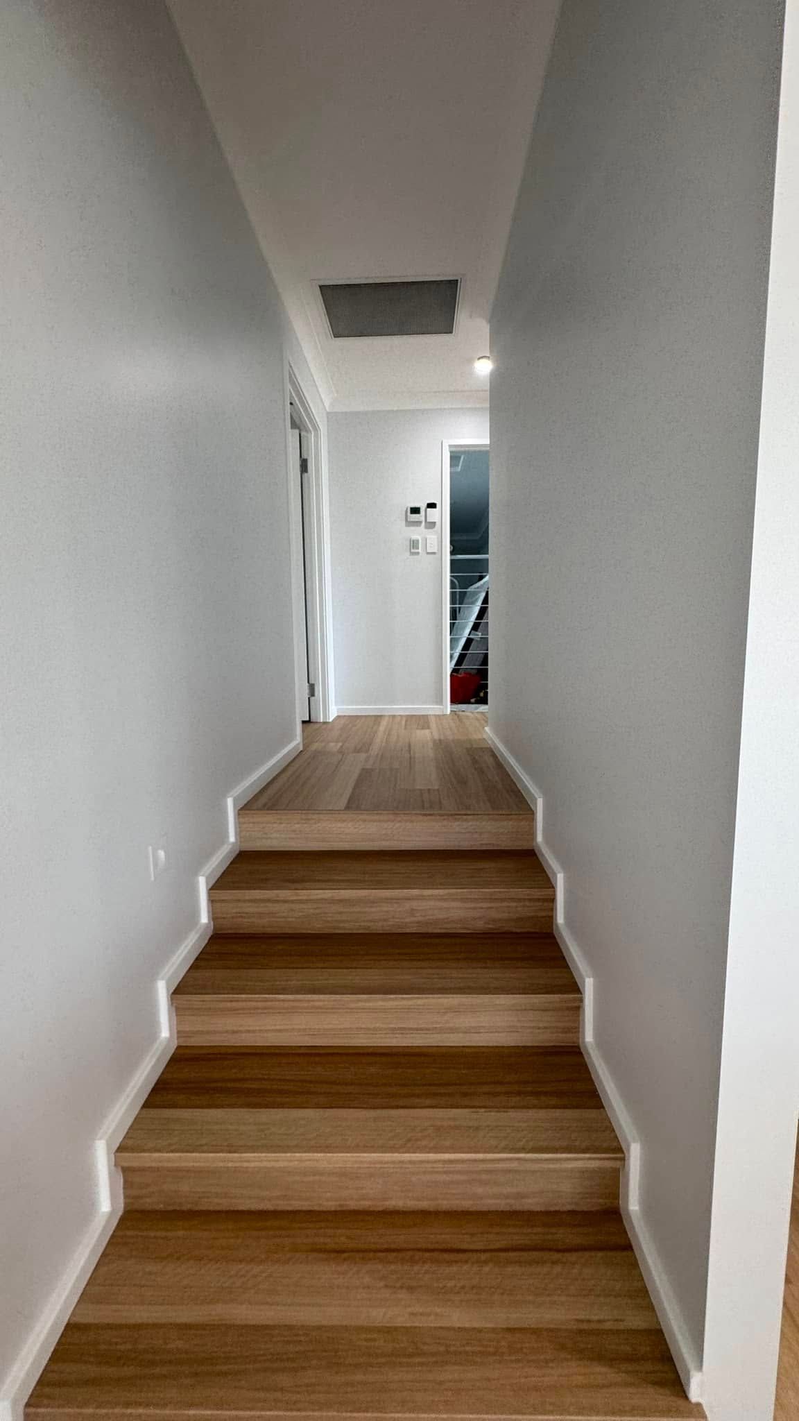 A Long Hallway With Wooden Stairs Leading Up to the Second Floor — JAX Painting Services in Central Coast, NSW