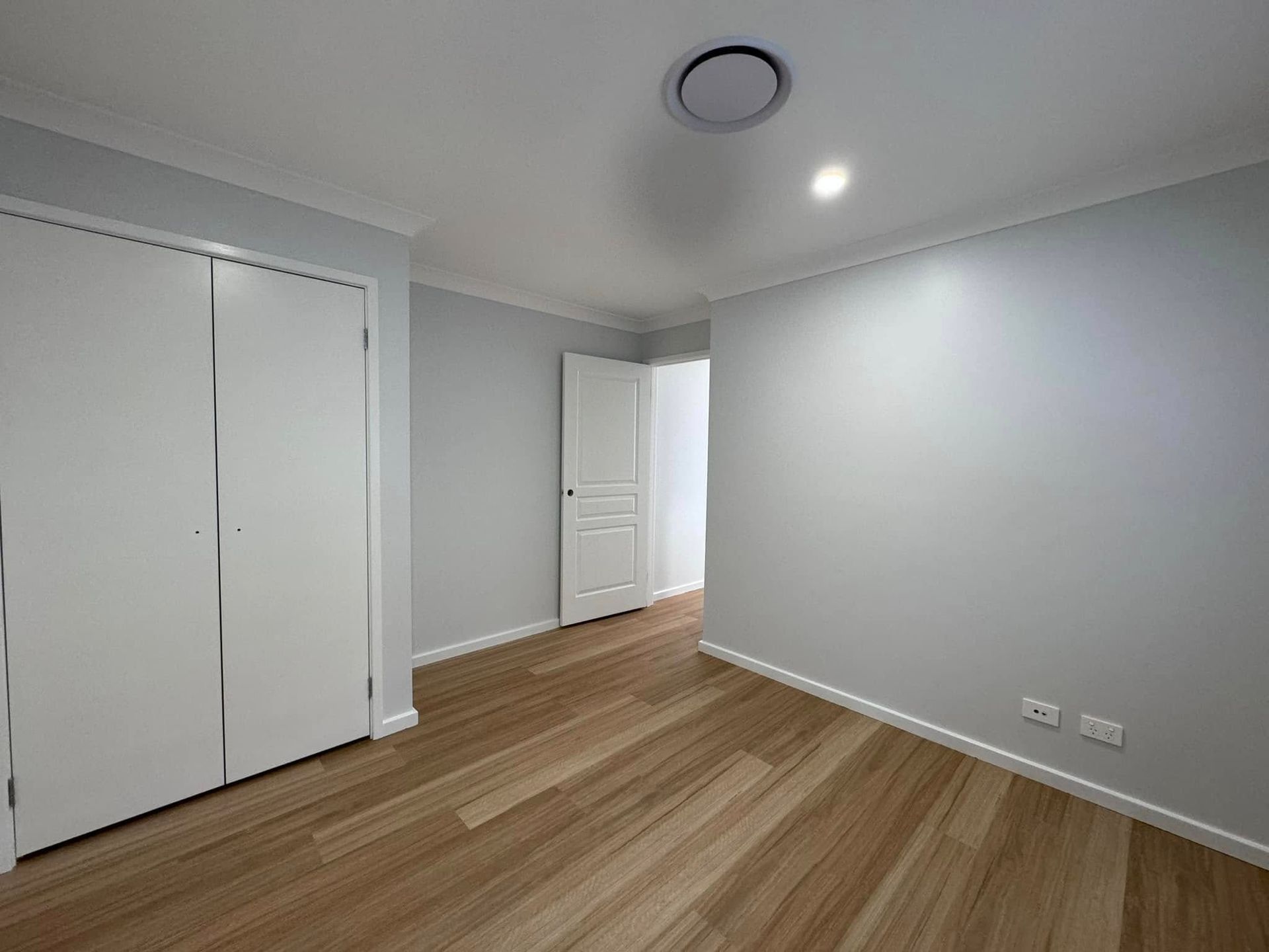 An Empty Bedroom With Hardwood Floors and White Walls — JAX Painting Services in Central Coast, NSW