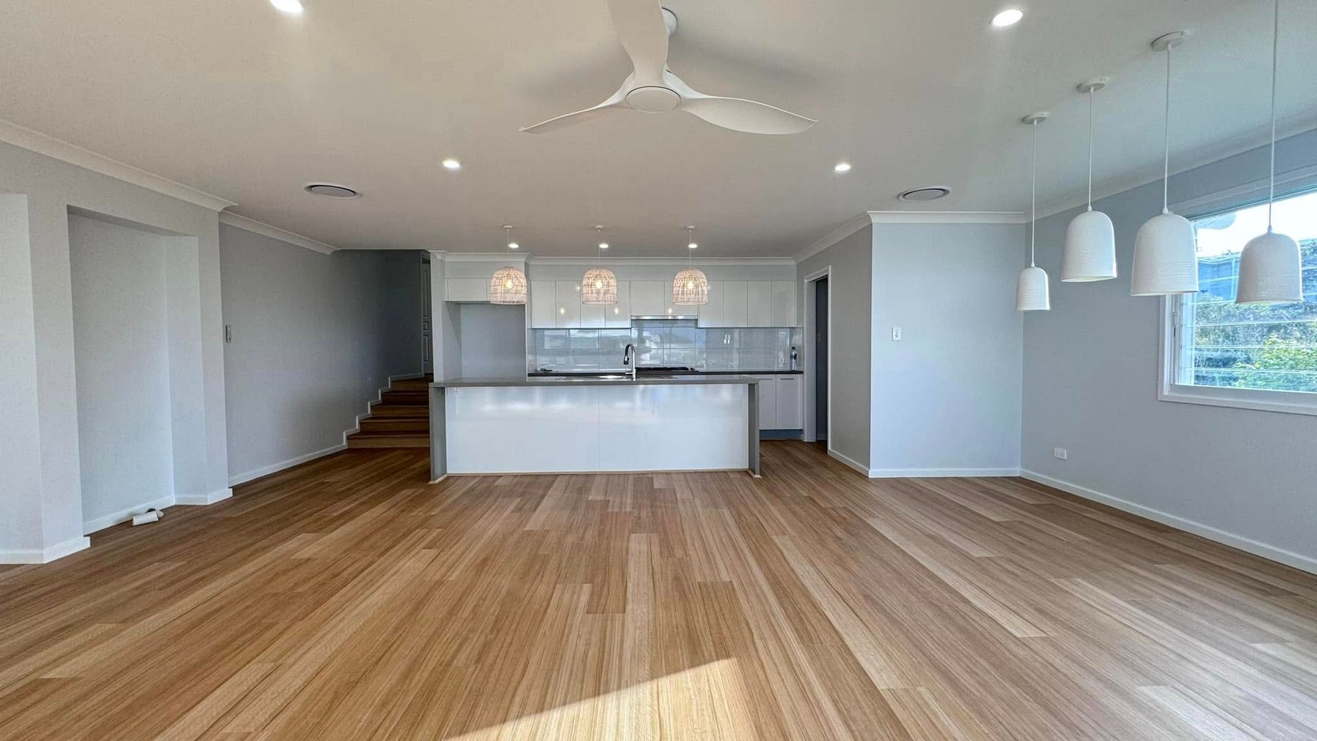 An Empty Living Room With Hardwood Floors and a Ceiling Fan — JAX Painting Services in Central Coast, NSW