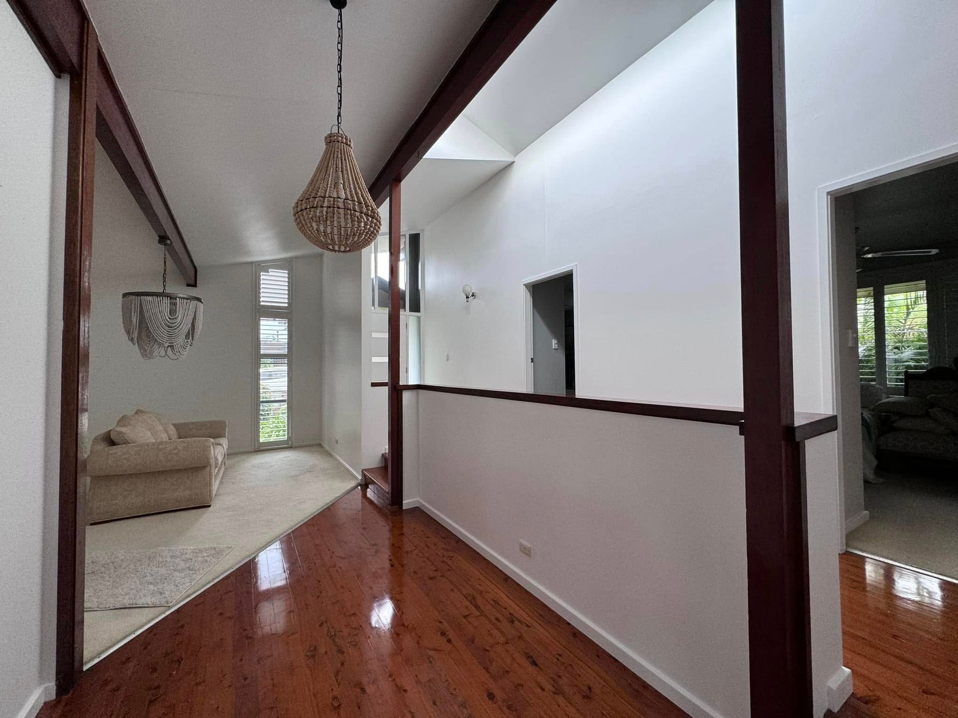 A Hallway in a House With Hardwood Floors and a Chandelier Hanging From the Ceiling — JAX Painting Services in Central Coast, NSW