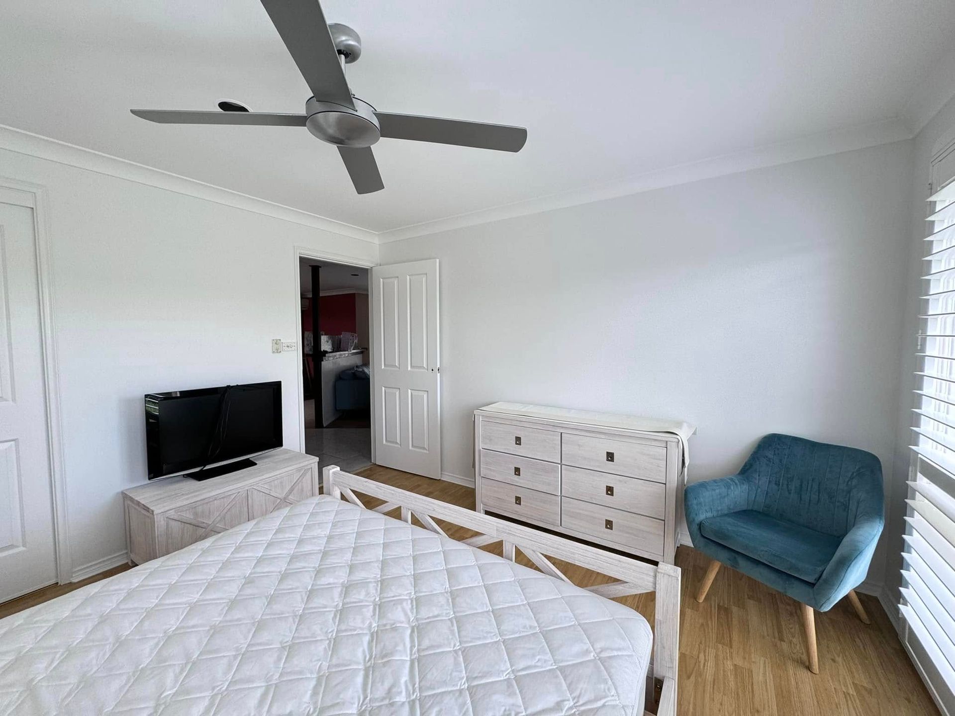 A Bedroom With a Bed, Dresser, Chair, Television and Ceiling Fan — JAX Painting Services in Central Coast, NSW