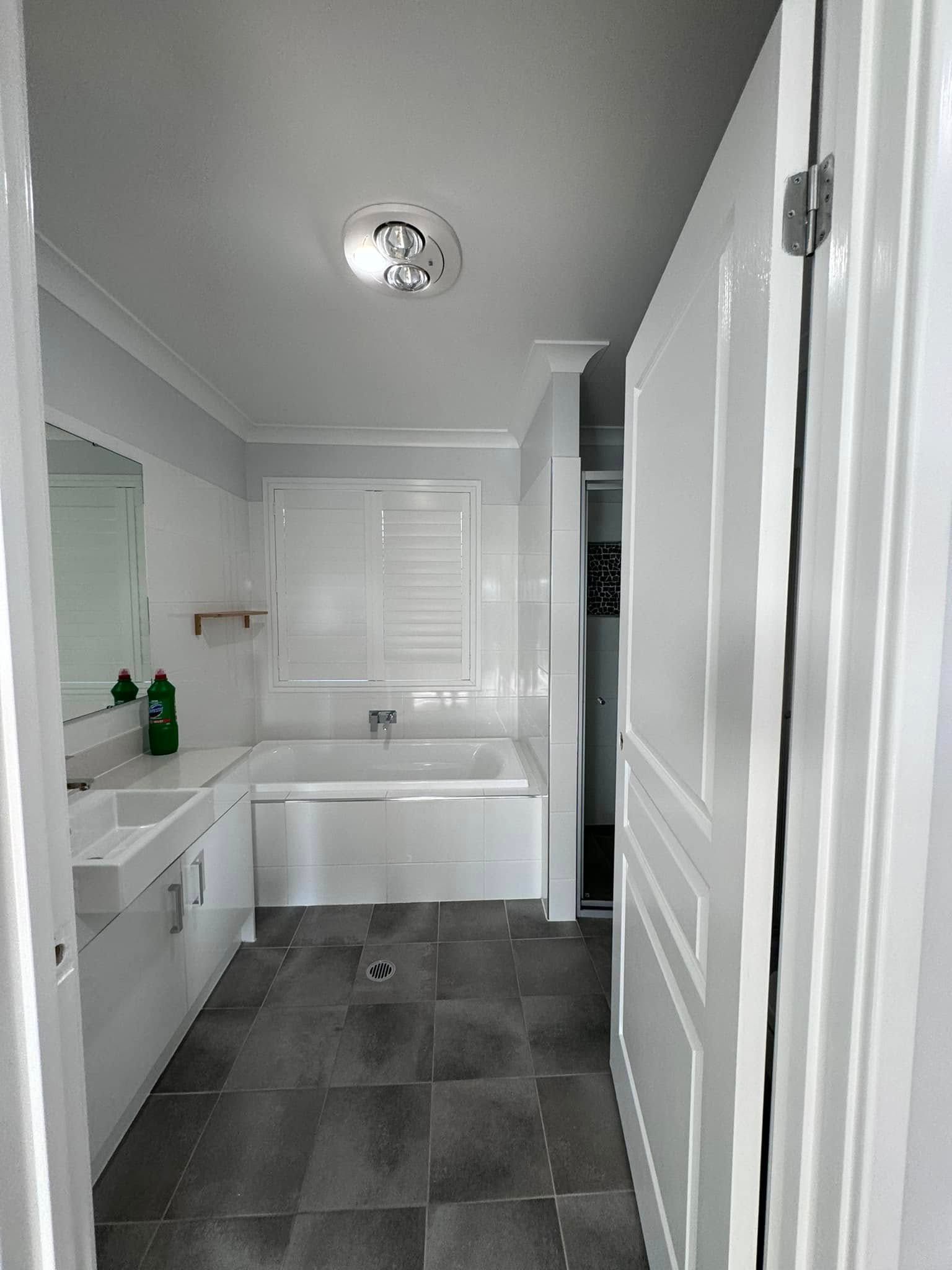 A Bathroom With a Bathtub, Sink and Mirror — JAX Painting Services in Central Coast, NSW