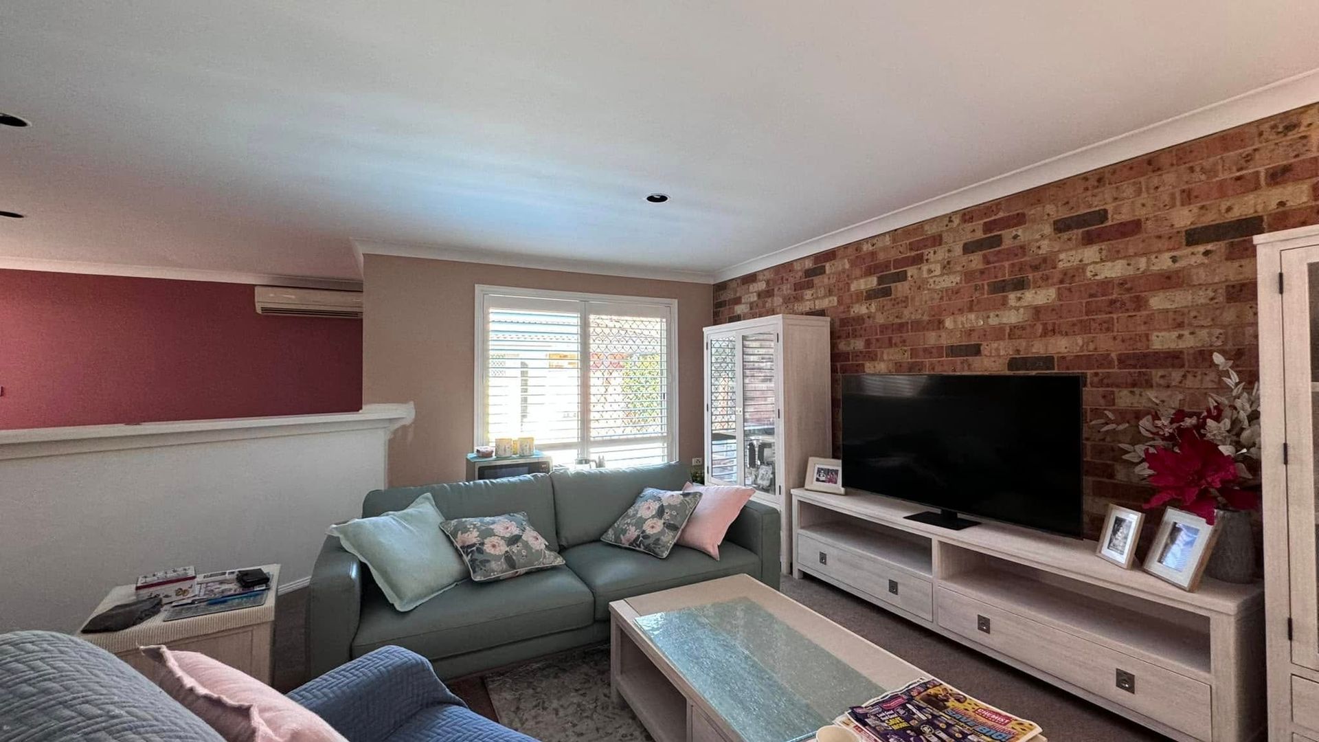 A Living Room With a Couch, Television, Coffee Table and Brick Wall — JAX Painting Services in Central Coast, NSW