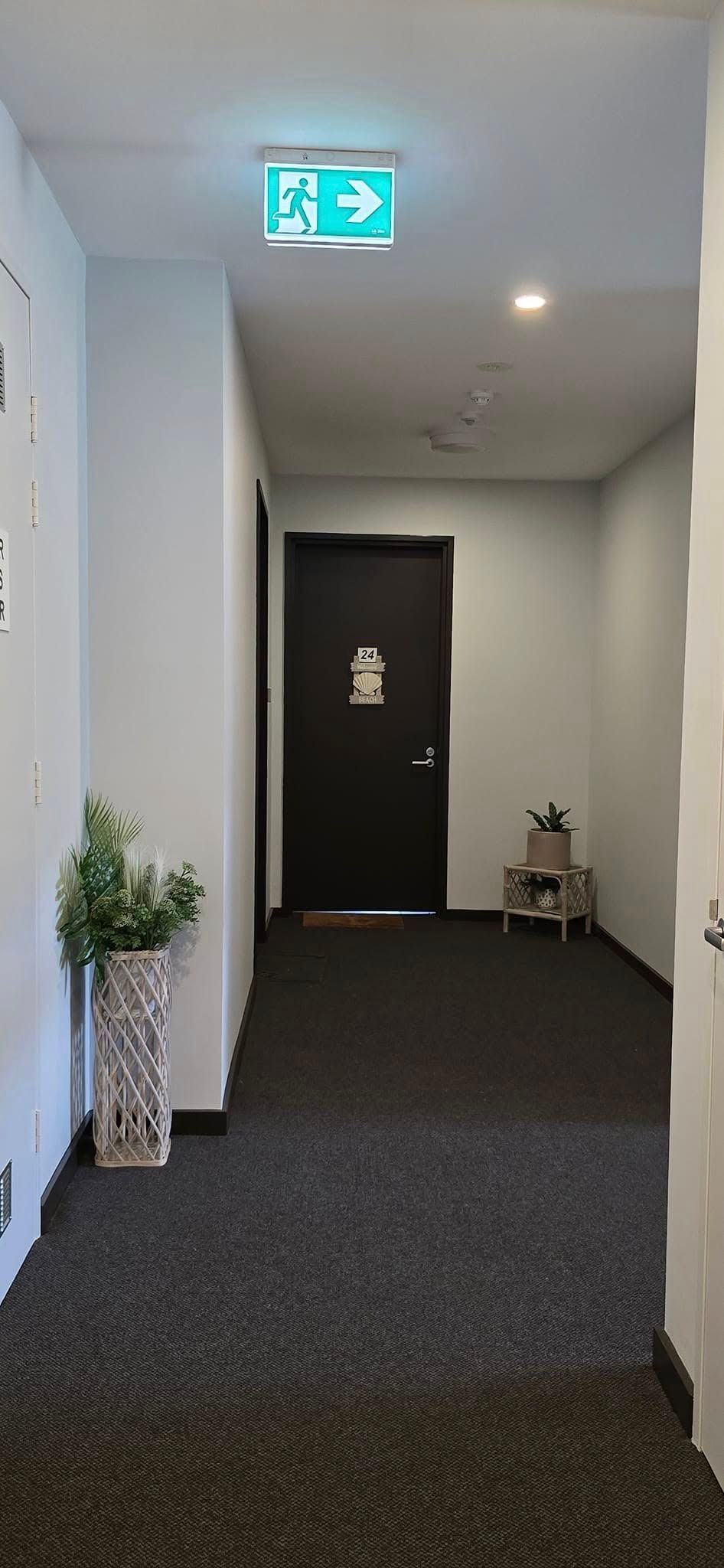 A Long Hallway With a Green Exit Sign on the Ceiling — JAX Painting Services in Central Coast, NSW