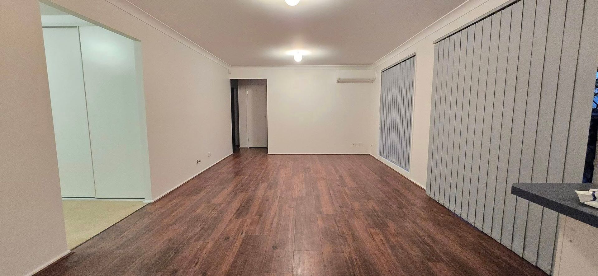 An Empty Living Room With Hardwood Floors and White Walls — JAX Painting Services in Central Coast, NSW