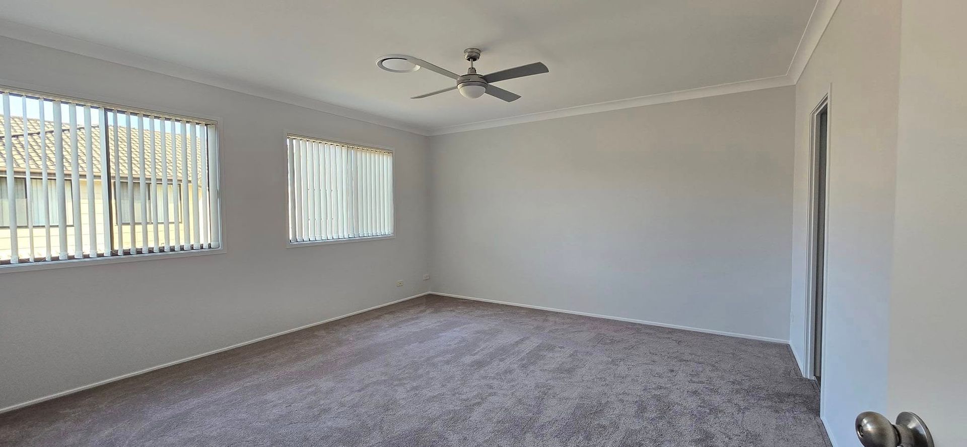 An Empty Living Room With a Ceiling Fan and Two Windows — JAX Painting Services in Central Coast, NSW