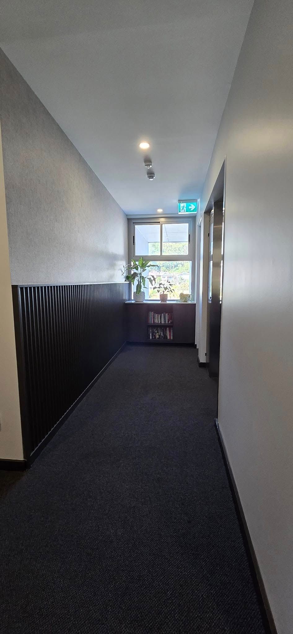 A Long Hallway With a Carpeted Floor and a Window — JAX Painting Services in Central Coast, NSW