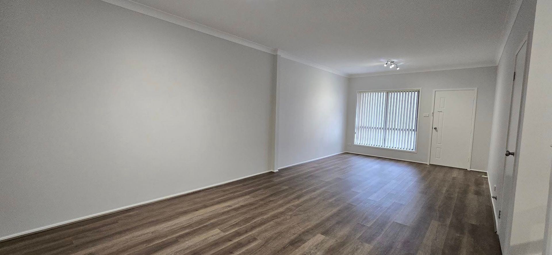 An Empty Living Room With Hardwood Floors and White Walls — JAX Painting Services in Central Coast, NSW