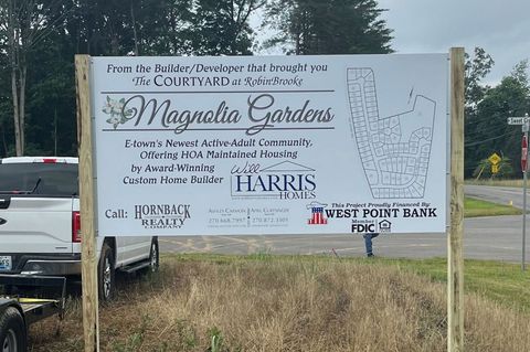 Outdoor sign for Magnolia Gardens event with sponsor logos, posted beside a roadside and parked truck. Outdoor sign for Magnolia Gardens event with sponsor logos, posted beside a roadside and parked truck.