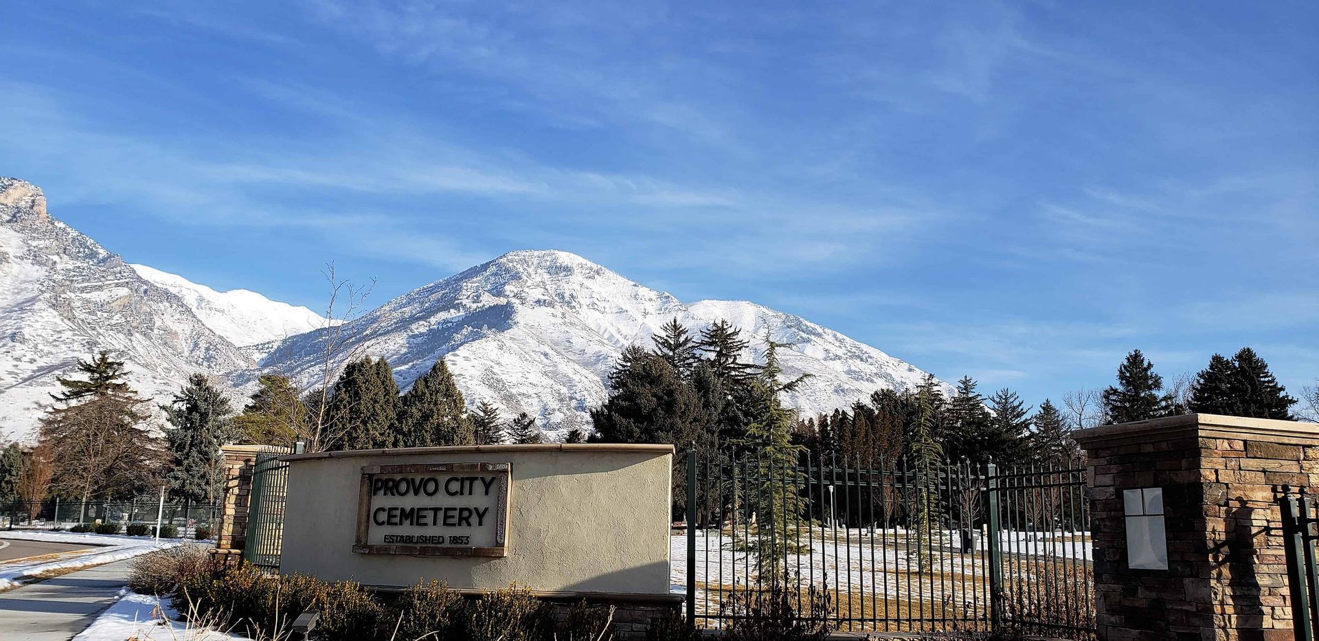 A professional view of grave markers at Provo City Cemetery with mountain backdrop.