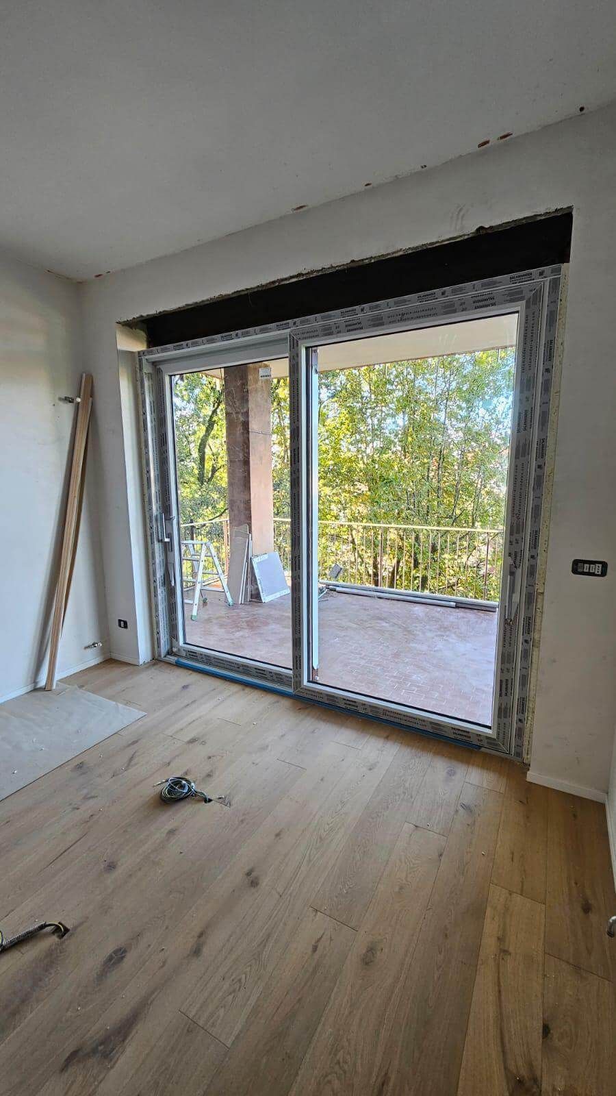 Una stanza vuota con una grande porta scorrevole in vetro che conduce a un balcone.