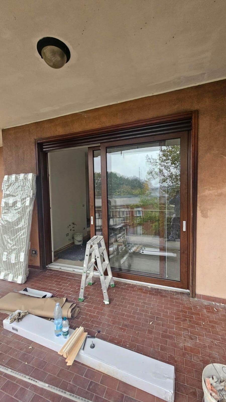 Una scala è appoggiata davanti a una grande porta scorrevole in vetro.