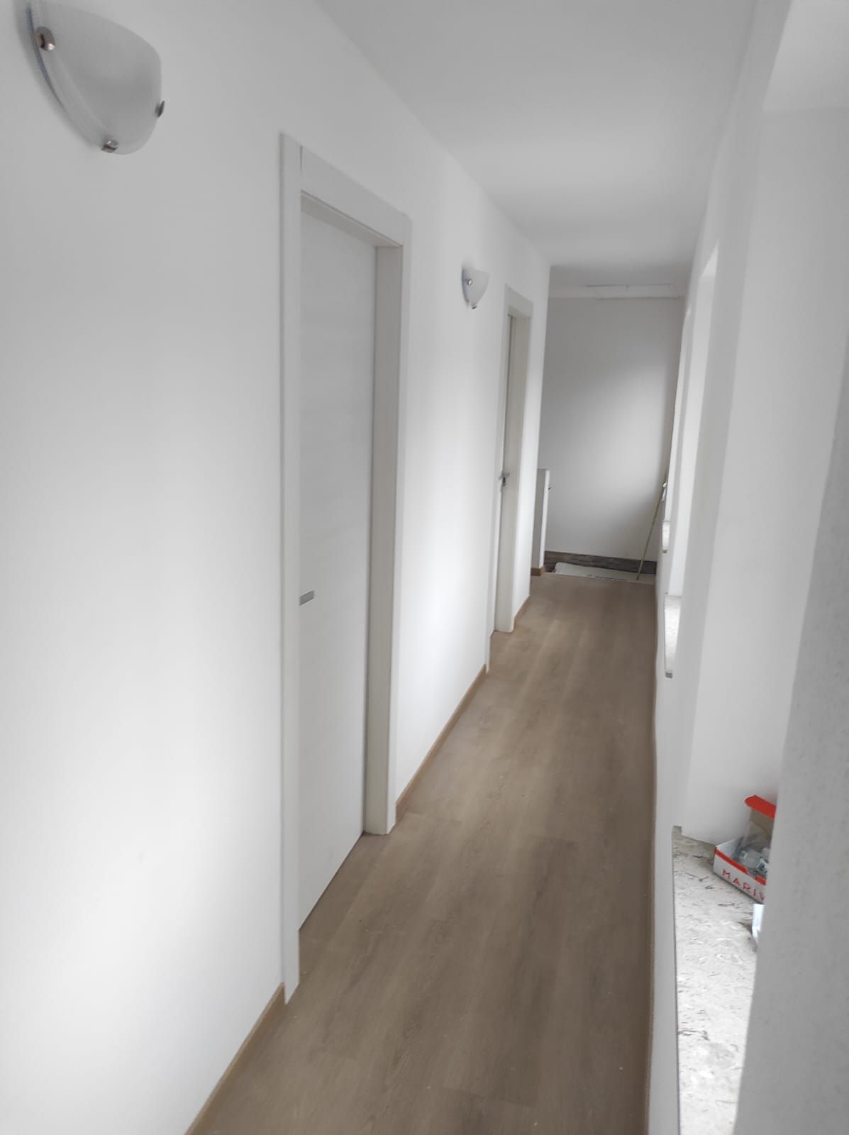 Un lungo corridoio con pareti bianche e pavimenti in legno