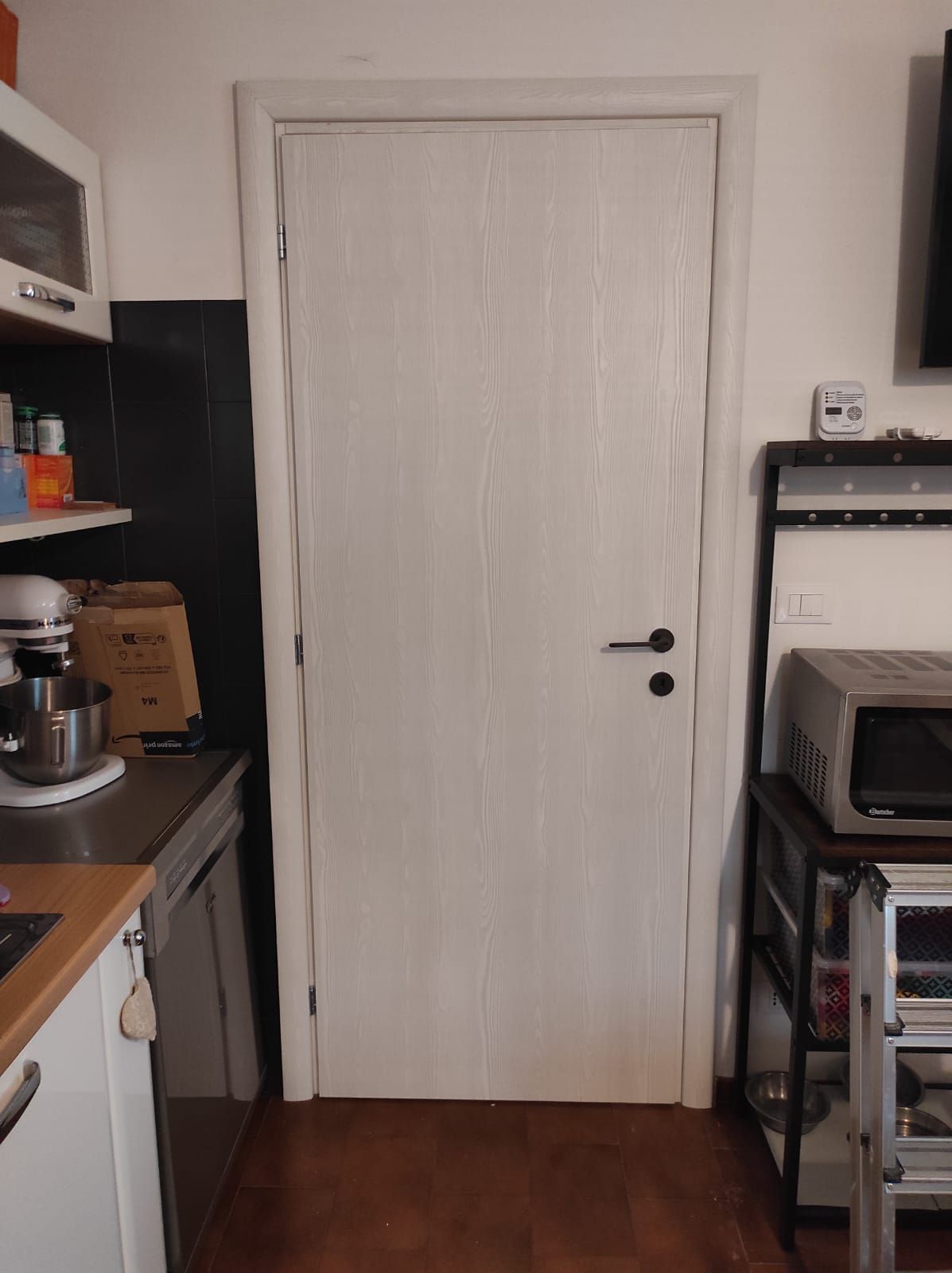 Una cucina con una porta bianca e una maniglia nera